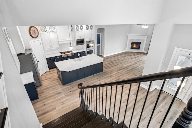 stairs with arched walkways, a tiled fireplace, wood finished floors, and a ceiling fan