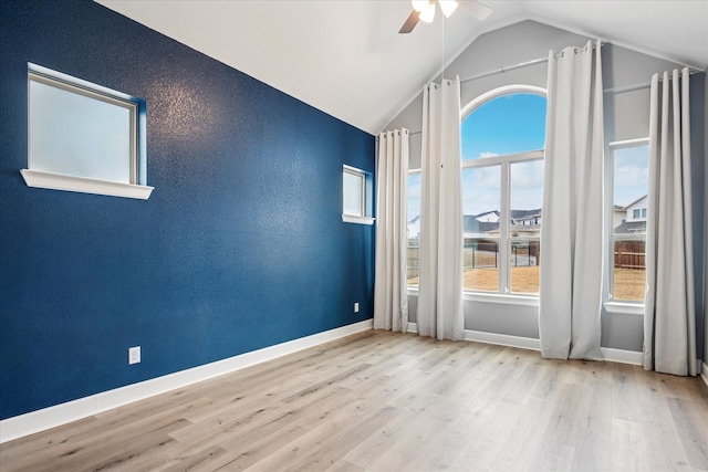 empty room featuring lofted ceiling, ceiling fan, baseboards, and wood finished floors