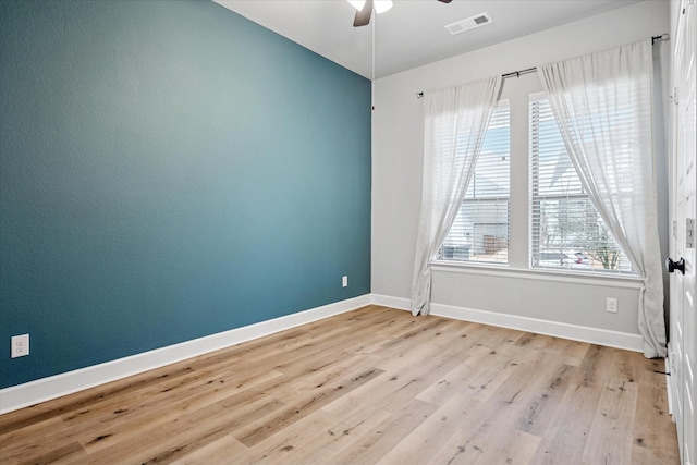 spare room with light wood-type flooring, visible vents, ceiling fan, and baseboards