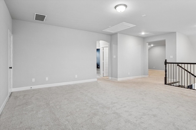 unfurnished room featuring light carpet, baseboards, visible vents, and arched walkways