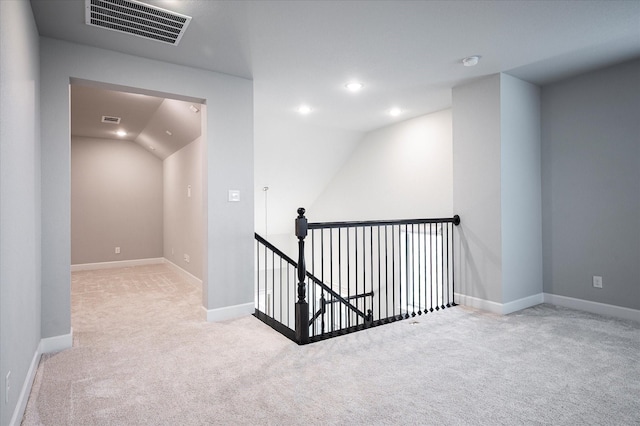 hall featuring baseboards, visible vents, carpet flooring, and an upstairs landing