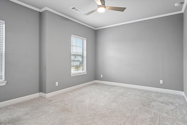 empty room with carpet, visible vents, crown molding, and ceiling fan