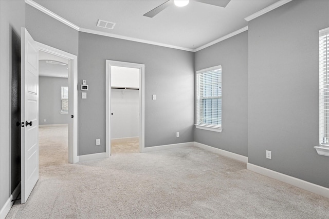 unfurnished bedroom with carpet floors, crown molding, visible vents, a spacious closet, and baseboards