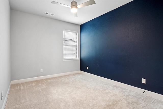 carpeted empty room featuring a ceiling fan, visible vents, and baseboards