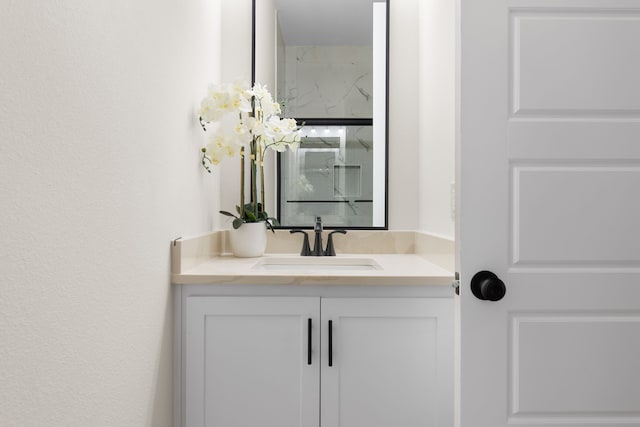 bathroom featuring a marble finish shower and vanity