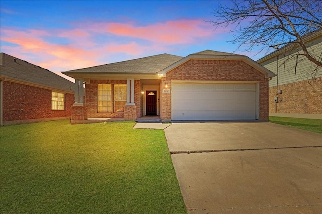 ranch-style house featuring driveway, brick siding, an attached garage, and a yard