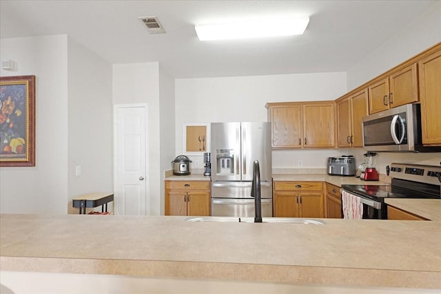 kitchen with stainless steel appliances, light countertops, visible vents, and a sink