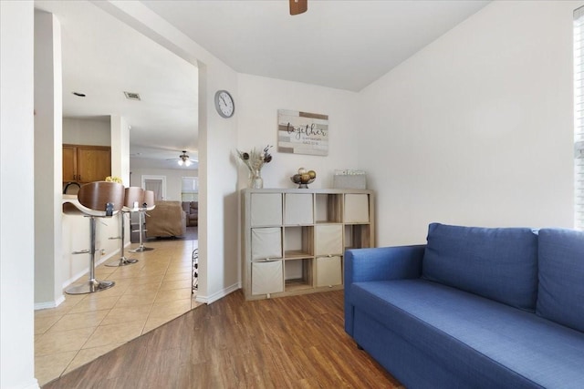 sitting room with light wood finished floors, ceiling fan, visible vents, and baseboards