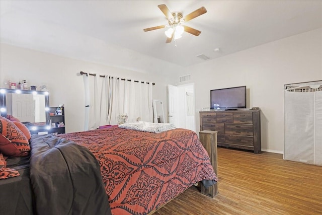 bedroom with baseboards, visible vents, ceiling fan, and wood finished floors