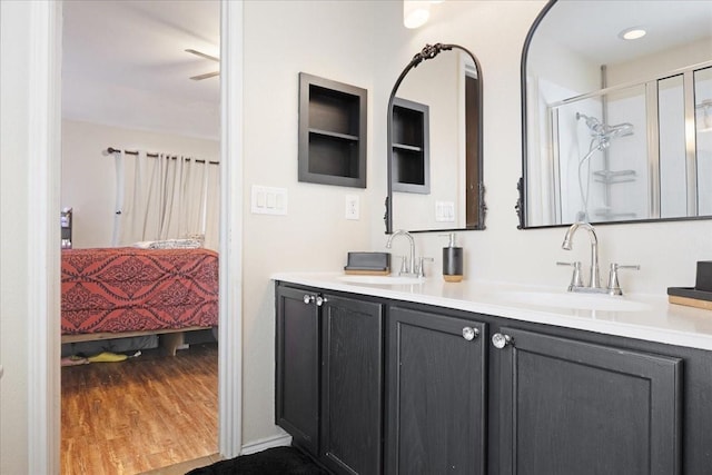 bathroom featuring a shower stall, connected bathroom, a sink, and wood finished floors