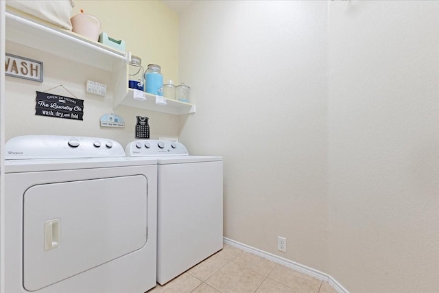 laundry area featuring washing machine and dryer, laundry area, light tile patterned flooring, and baseboards