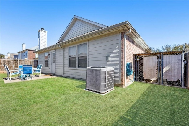 rear view of property with brick siding, a yard, a chimney, central AC, and a fenced backyard