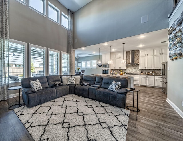 living area featuring dark wood-type flooring, recessed lighting, a towering ceiling, and baseboards