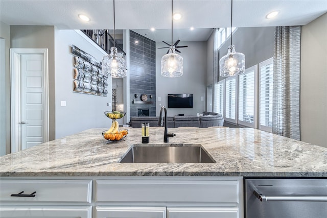 kitchen with recessed lighting, a sink, white cabinetry, open floor plan, and light stone countertops