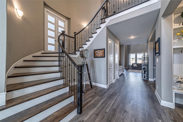 entrance foyer with dark wood-style floors, a high ceiling, baseboards, and stairs