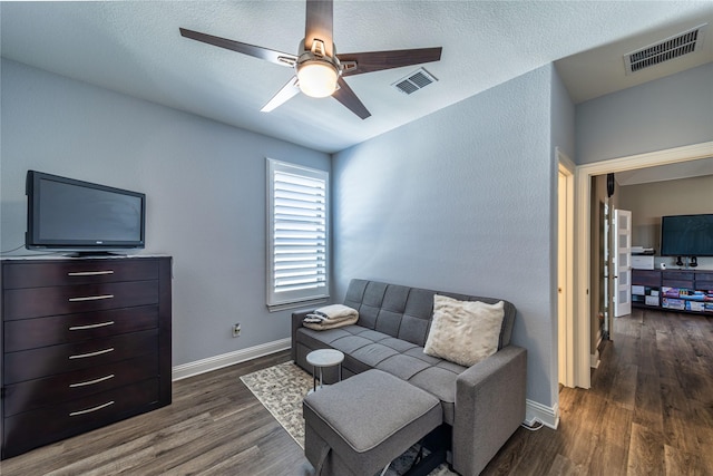 living room featuring a ceiling fan, baseboards, visible vents, and dark wood-type flooring