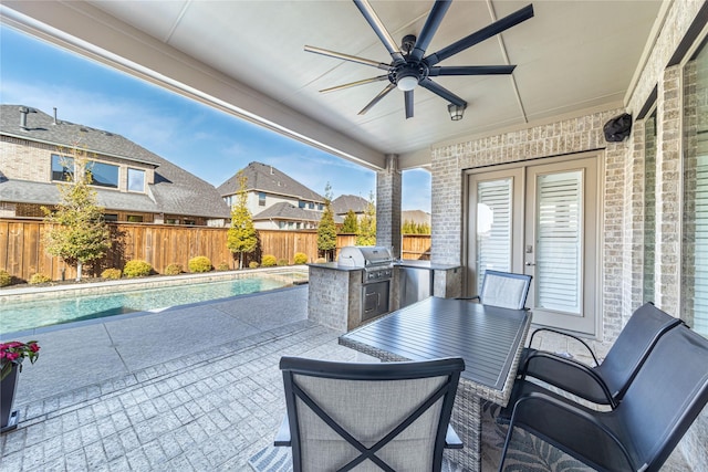 view of patio / terrace featuring an outdoor kitchen, a ceiling fan, area for grilling, a fenced backyard, and outdoor dining space