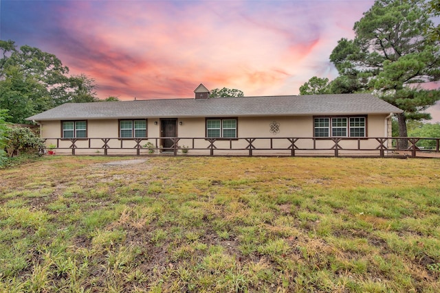 ranch-style house featuring fence, a front lawn, and stucco siding