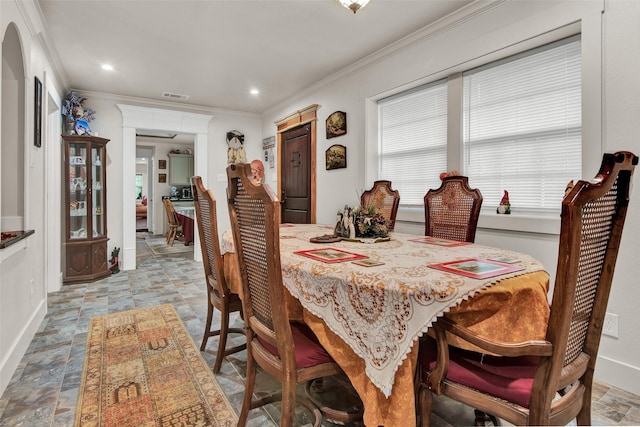 dining area with stone finish flooring, visible vents, and crown molding