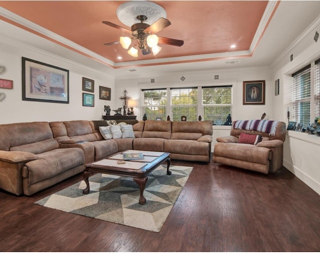 living room featuring a raised ceiling, crown molding, baseboards, and wood finished floors