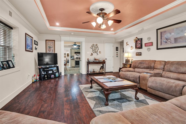 living room featuring baseboards, ceiling fan, ornamental molding, wood finished floors, and a tray ceiling