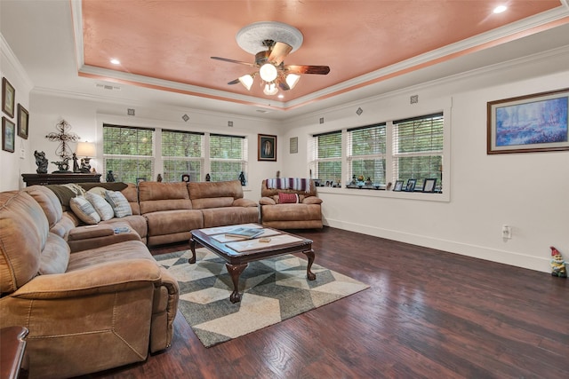 living room with wood finished floors, a ceiling fan, visible vents, baseboards, and a tray ceiling