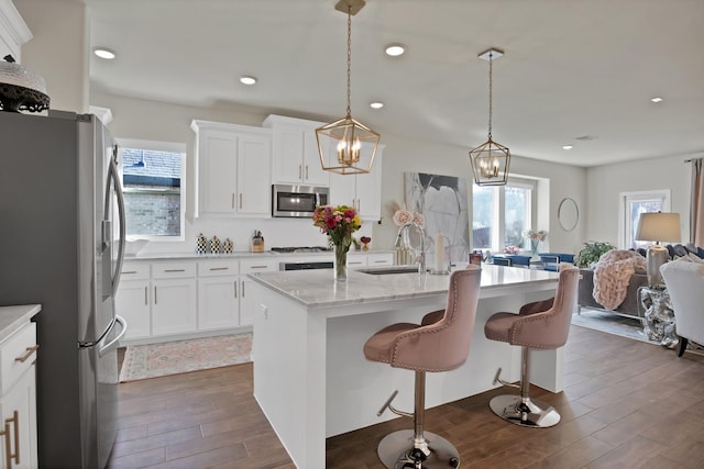 kitchen with dark wood-style floors, appliances with stainless steel finishes, a sink, and white cabinets