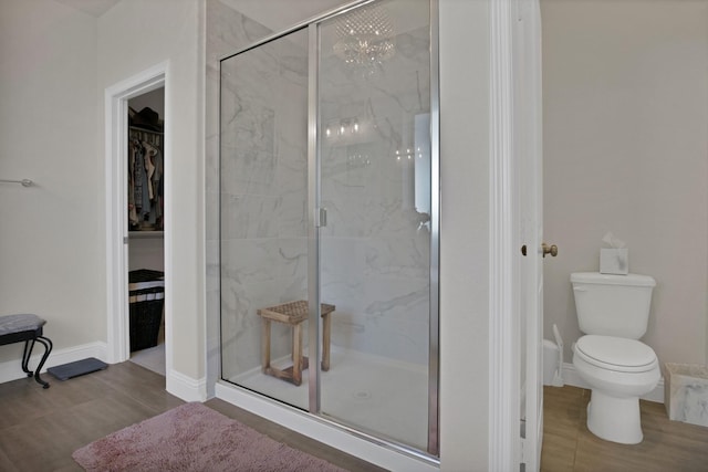 full bathroom with toilet, a spacious closet, a marble finish shower, and wood finished floors