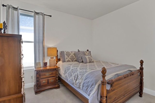 bedroom featuring multiple windows, baseboards, and light colored carpet