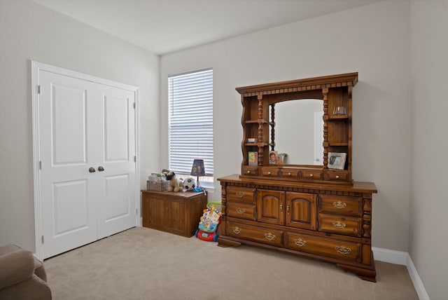 bedroom with light carpet, multiple windows, a closet, and baseboards