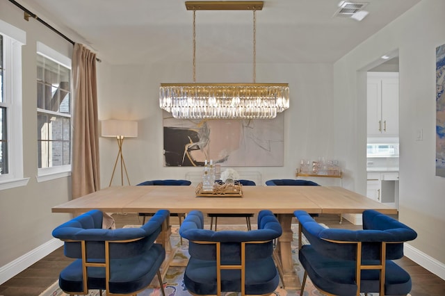 dining space with a chandelier, visible vents, baseboards, and wood finished floors