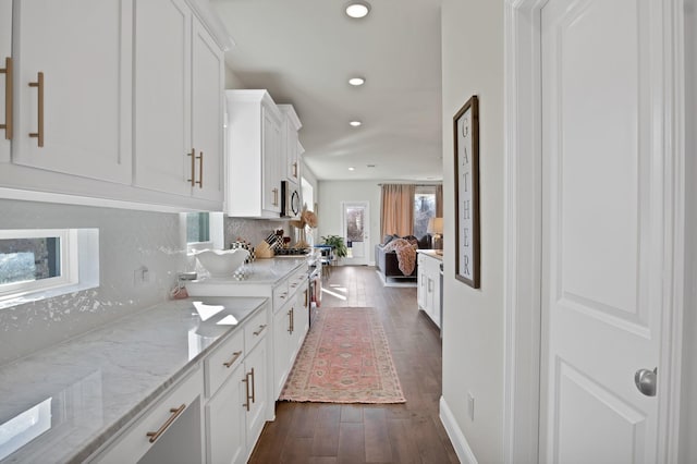 kitchen featuring light stone counters, dark wood-style flooring, backsplash, appliances with stainless steel finishes, and white cabinetry