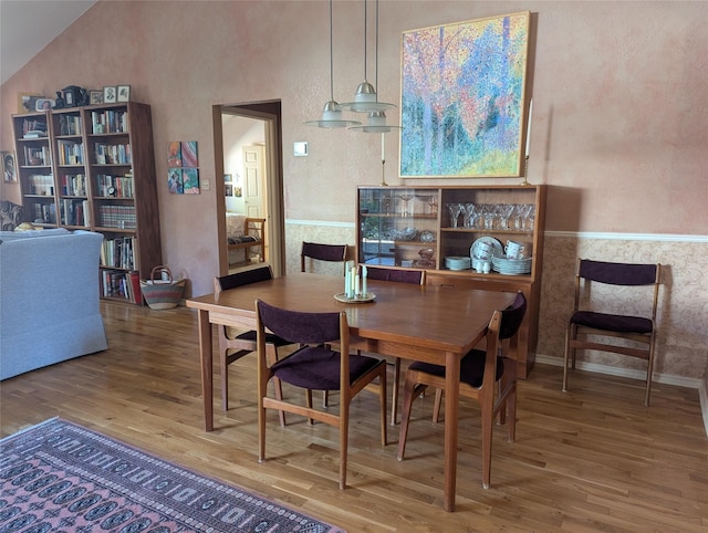 dining room featuring vaulted ceiling, baseboards, and wood finished floors