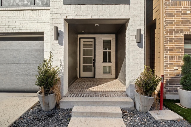 view of exterior entry featuring brick siding and an attached garage