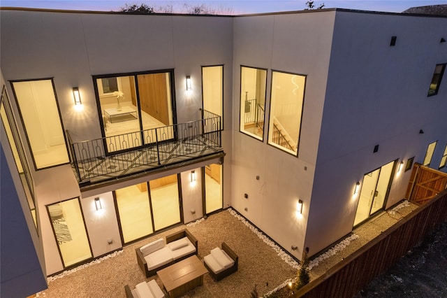 rear view of house with a balcony and stucco siding