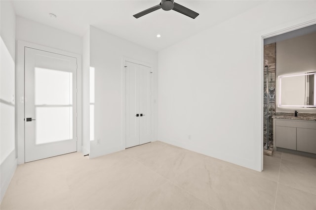 unfurnished bedroom with a closet, a sink, a ceiling fan, and baseboards