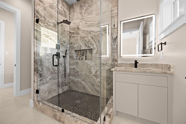 bathroom with baseboards, a shower stall, vanity, and tile patterned floors