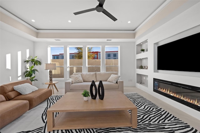 living room featuring built in features, crown molding, recessed lighting, a glass covered fireplace, and ceiling fan