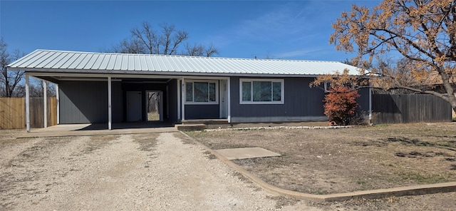 single story home featuring metal roof, fence, and driveway