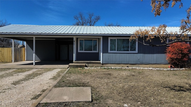 view of front facade with metal roof, an attached carport, and fence