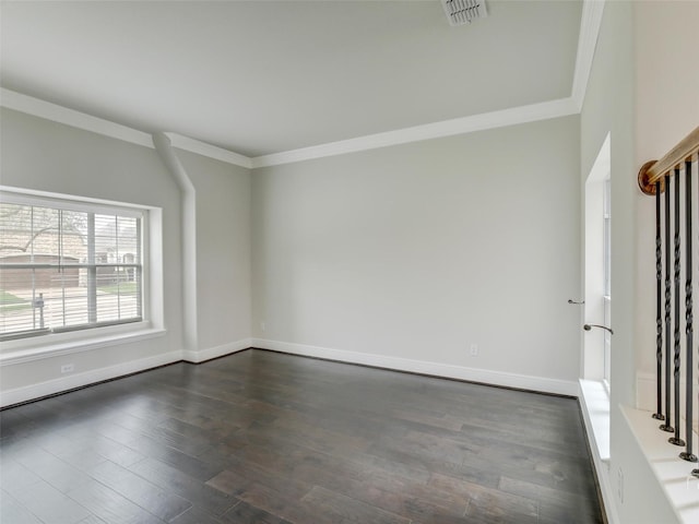 empty room with baseboards, dark wood finished floors, visible vents, and crown molding