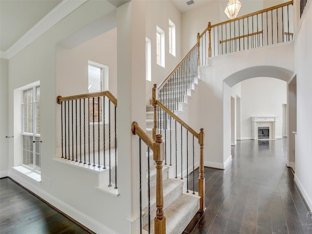 staircase with a towering ceiling, baseboards, and wood finished floors