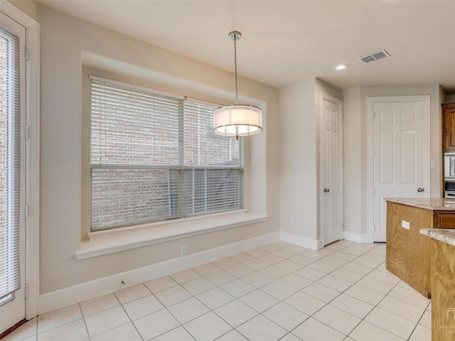 unfurnished dining area with light tile patterned floors, baseboards, visible vents, and a wealth of natural light