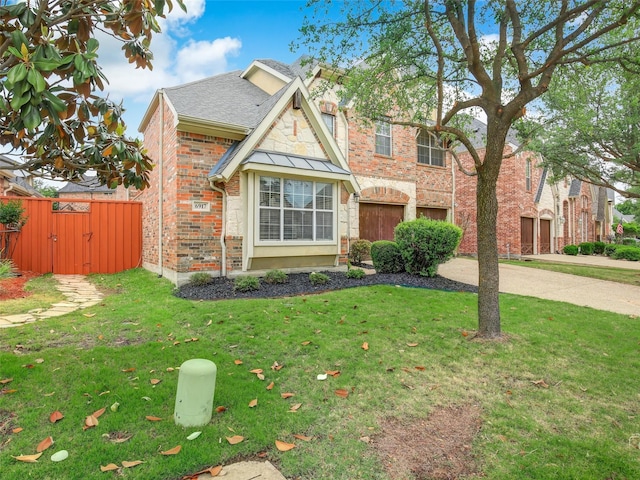 view of front of property with driveway, a garage, fence, a front lawn, and brick siding