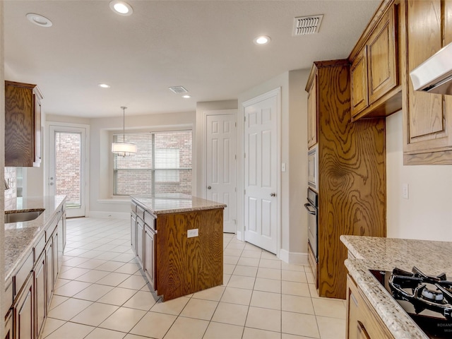 kitchen featuring brown cabinets, light tile patterned floors, visible vents, black appliances, and extractor fan