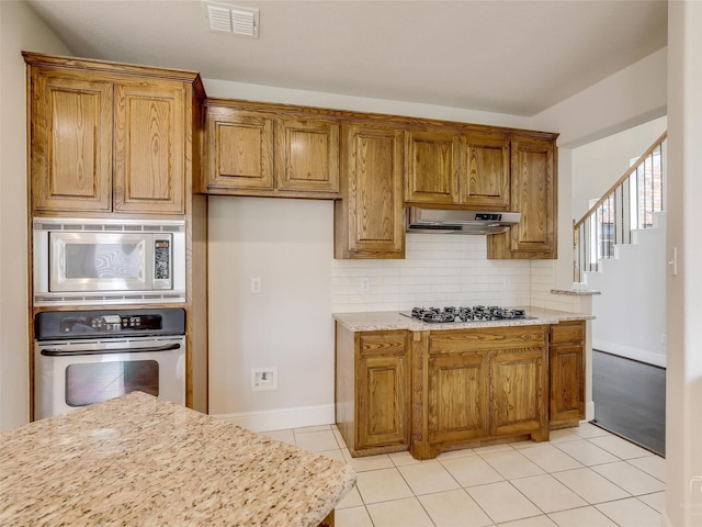 kitchen with brown cabinets, tasteful backsplash, visible vents, appliances with stainless steel finishes, and under cabinet range hood