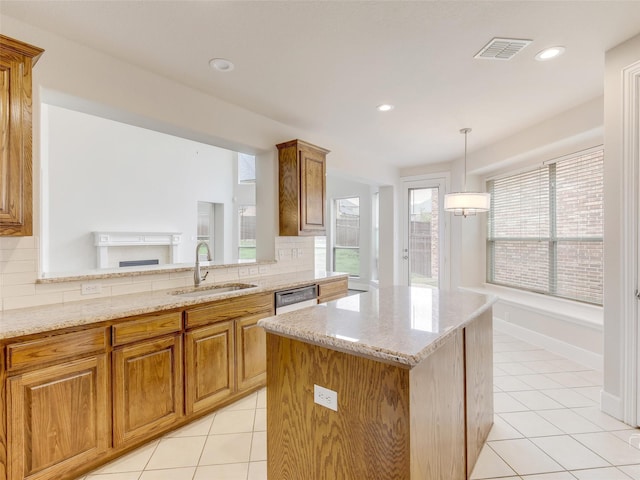 kitchen featuring dishwashing machine, brown cabinetry, a sink, and light tile patterned flooring