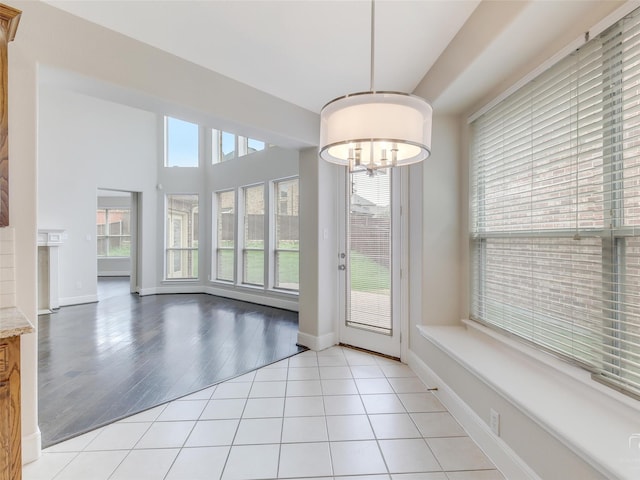 doorway featuring tile patterned floors, baseboards, and an inviting chandelier