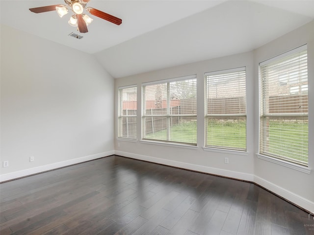 spare room featuring visible vents, vaulted ceiling, dark wood-style floors, and a wealth of natural light