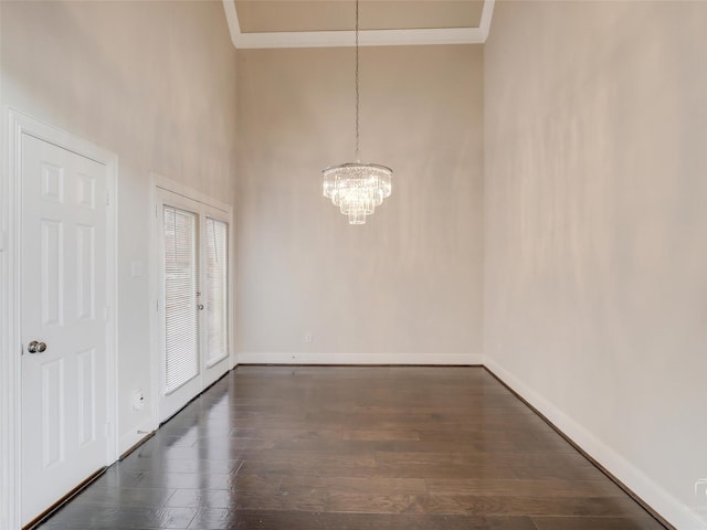 unfurnished dining area featuring dark wood-style floors, crown molding, and baseboards